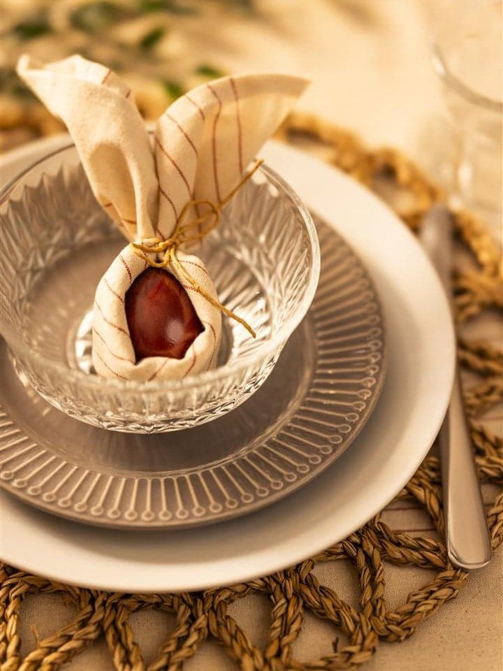 Sur une assiette, une serviette sert de décoration et, à l'intérieur, se trouve un œuf rouge.