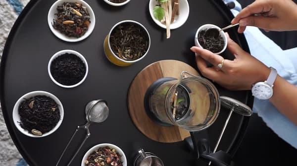 Sur une table, plusieurs feuilles de thé mélangées pour créer une infusion unique.