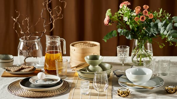 Sur une table, trois styles différents de couvert, avec de la vaisselle, des verres, des sets et des vases de fleurs différents.
