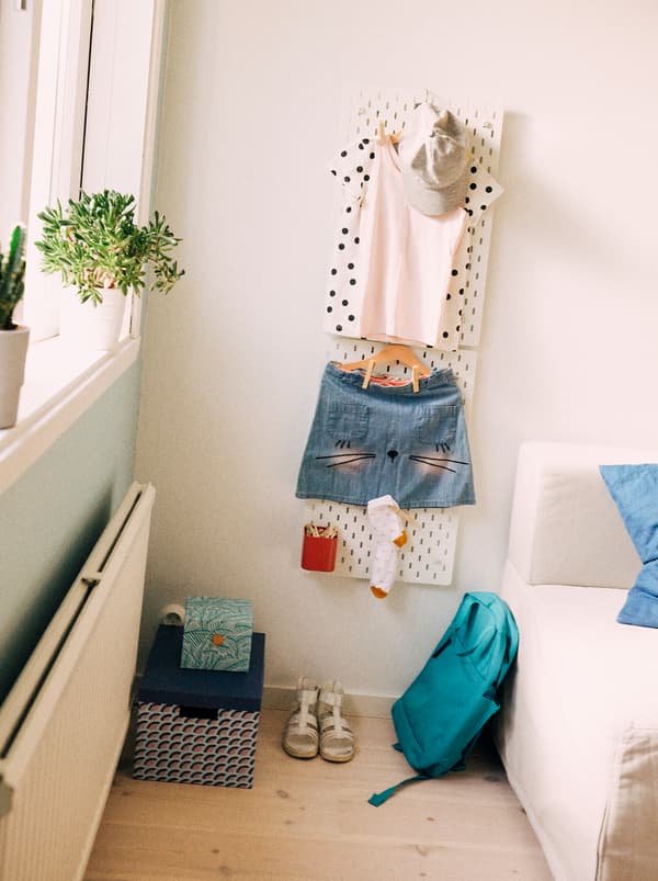 Suspendue à un panneau perforé SKÅDIS, la tenue d’une jeune fille pour l’école est prête pour le lendemain, y compris ses chaussettes, son sac à dos et ses chaussures.