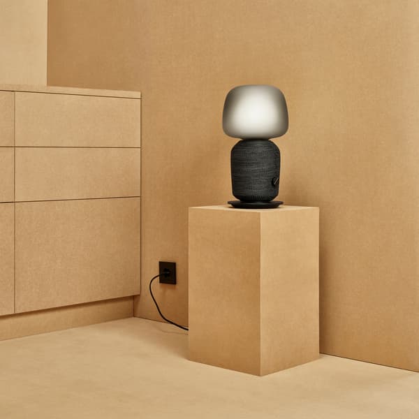 Svart högtalarlampa står på en beige piedestal
