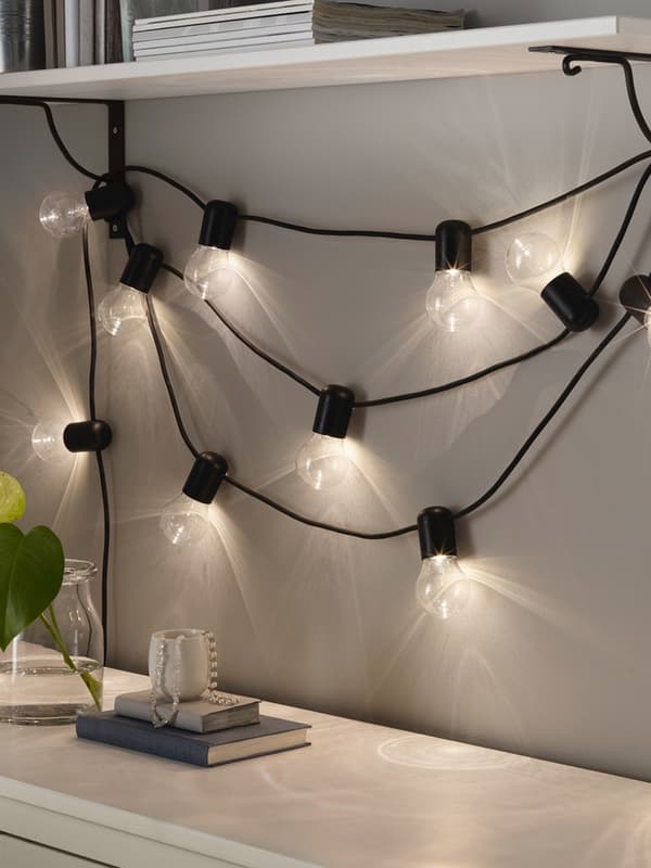 SVARTRÅ lighting chain draped under a shelf.