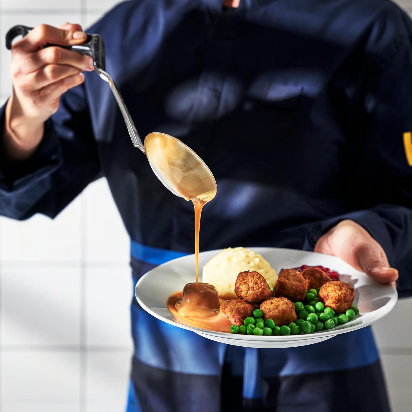 Švédské kuličky s přílohou v restauraci podávané zaměstnancem IKEA Food