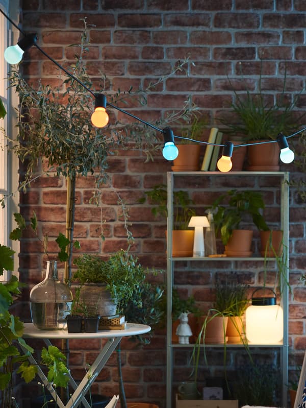 Svetelná reťaz SOLVINDEN na balkóne nad skladacím stolíkom SUNDSÖ.