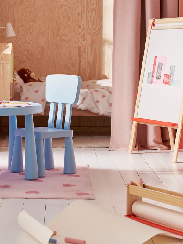 Svetlomodrý detský stôl a stolička MAMMUT, vedľa nich stojí maliarsky stojan MÅLA a pred ním je držiak na rolku papiera MÅLA.