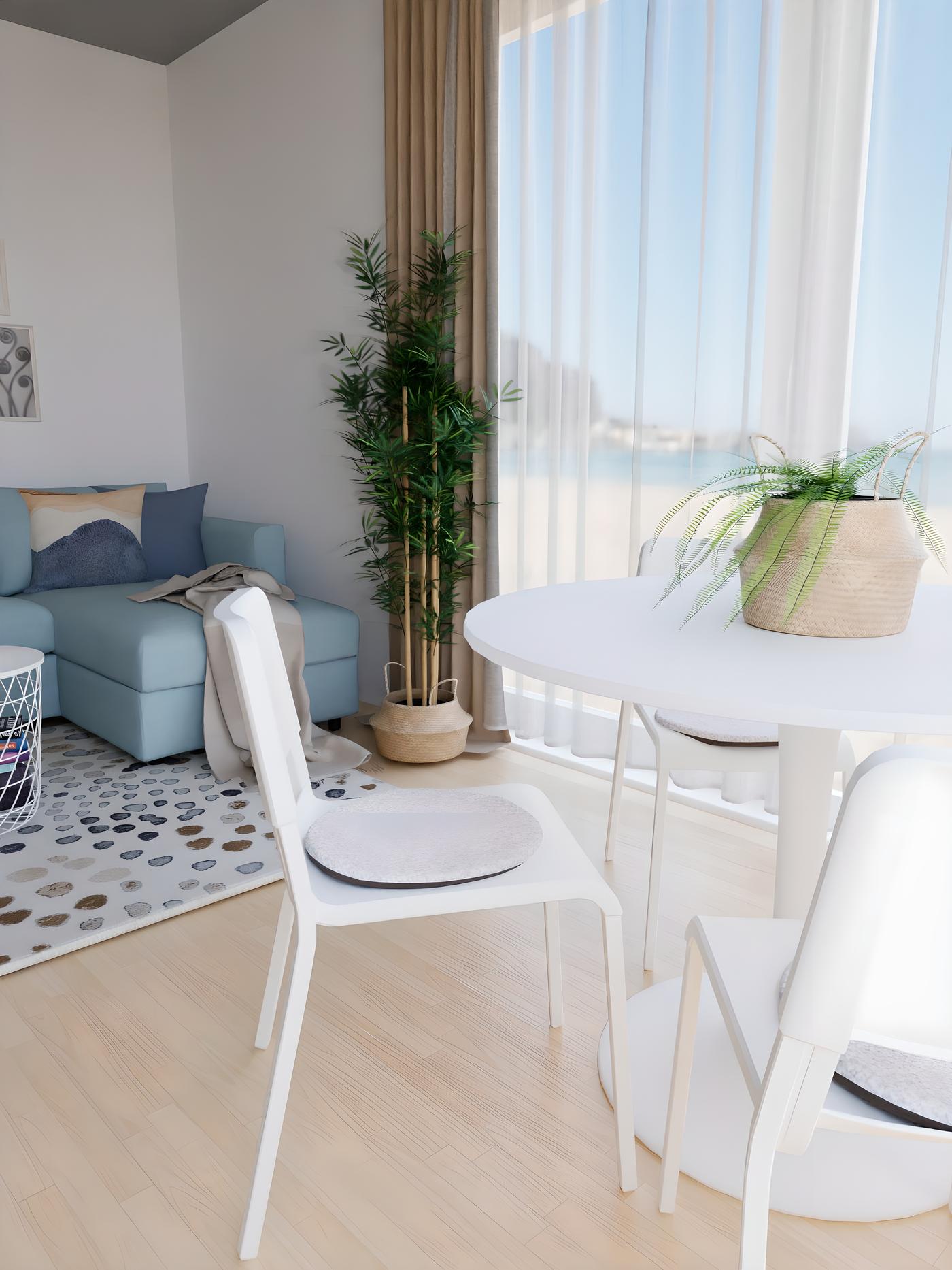 Svijetla dnevna soba s bijelim stolom, dvije bijele stolice, plavim kaučem i zelenom biljkom pored prozora.