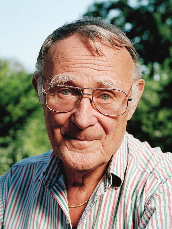 صورة لمؤسس ايكيا Ingvar Kamprad، وهو يبتسم في مكان مفتوح ويرتدي قميصًا مخططًا باللون الوردي والأبيض والأخضر.