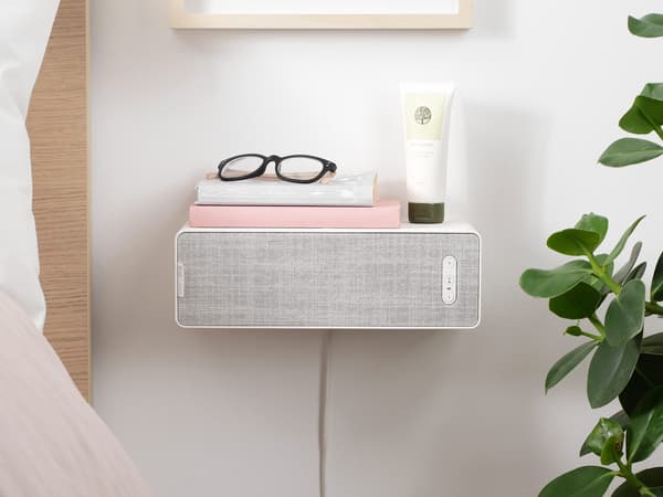 SYMFONISK bookshelf WiFi speaker wallmounted as a bedside table next to a bed.