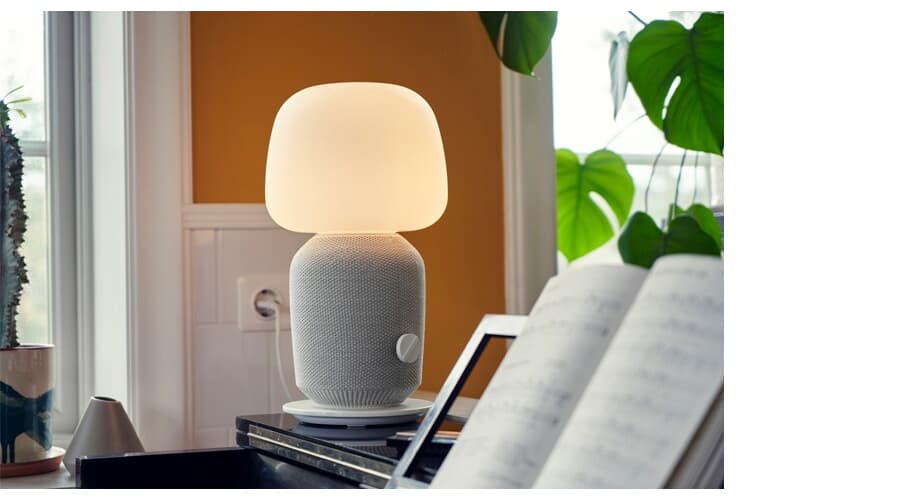 SYMFONISK lamp on a table in a living room setting.