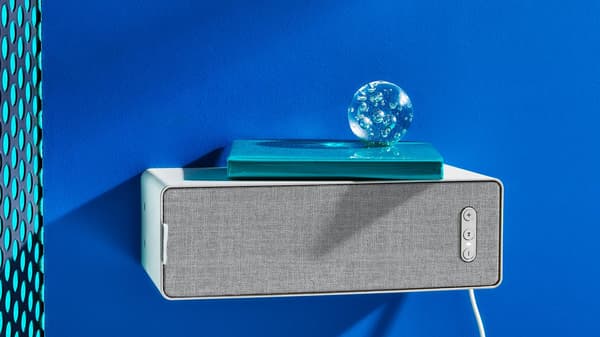 SYMFONISK WiFi speaker is attached to the wall and there is a book and an objet on the speaker.