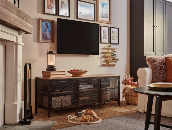 Szafka pod TV z serii FJÄLLBO i wiszące na ścianie telewizor i obrazki w ramkach.