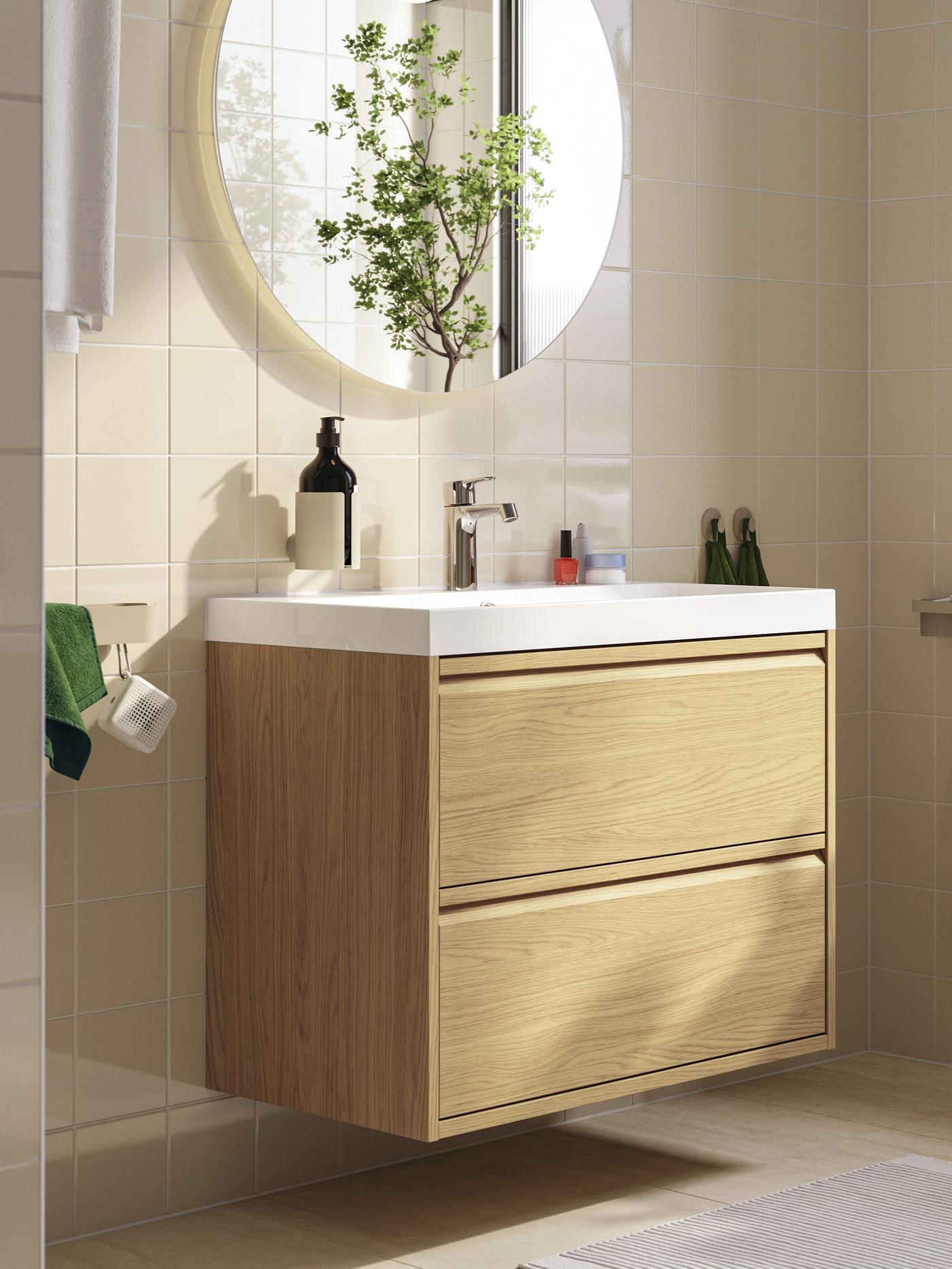Szafka umywalkowa ÄNGSJÖN/BACKSJÖN w imitacji dębu, z dwiema szufladami i umywalką, ustawiona pod okrągłym lustrem w nowoczesnej łazience.