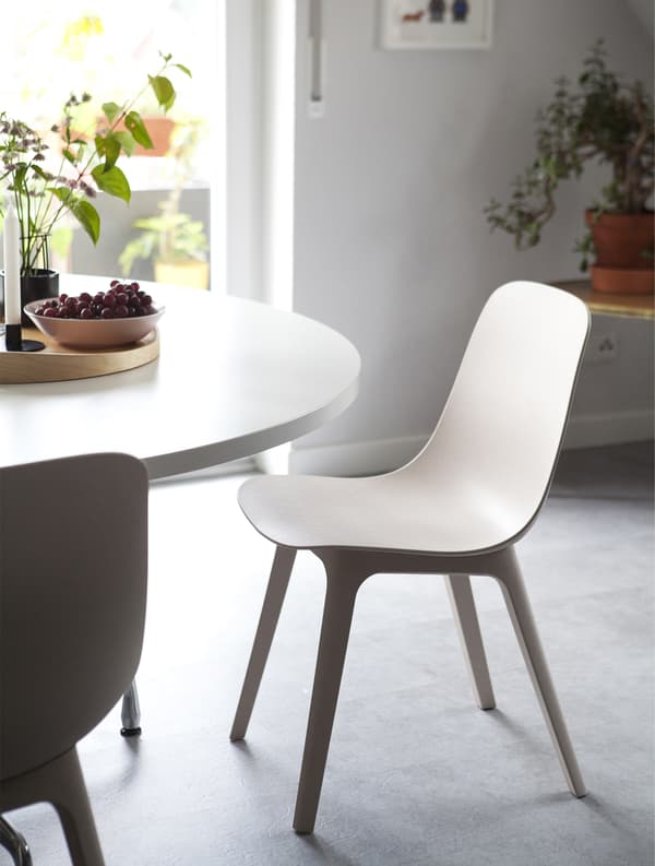 Table blanche ronde et chaises beige et blanc.