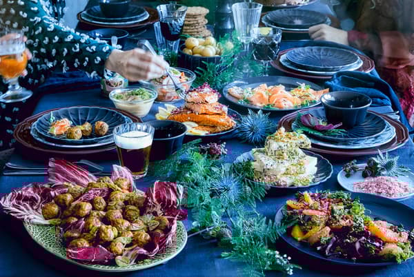Table covered with a blue tablecloth and plates with meatballs, veggieballs, salmon