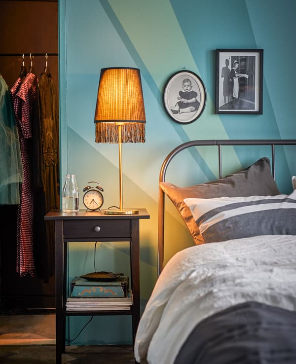 Table de chevet avec lampe dorée à franges, à côté du lit.