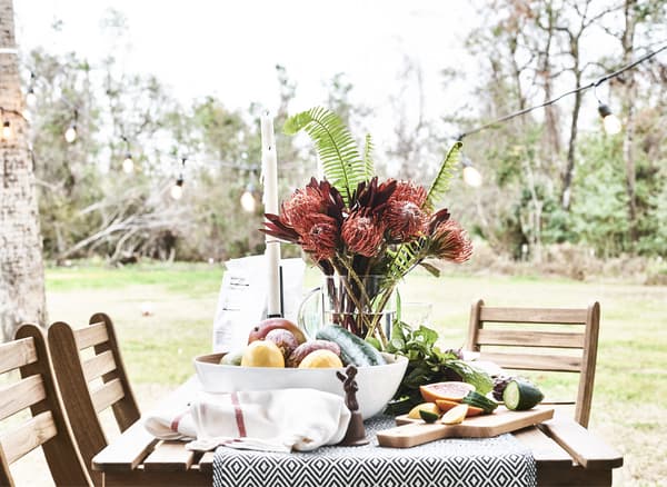 Table dressée à l’extérieur, avec fleurs et produits frais.