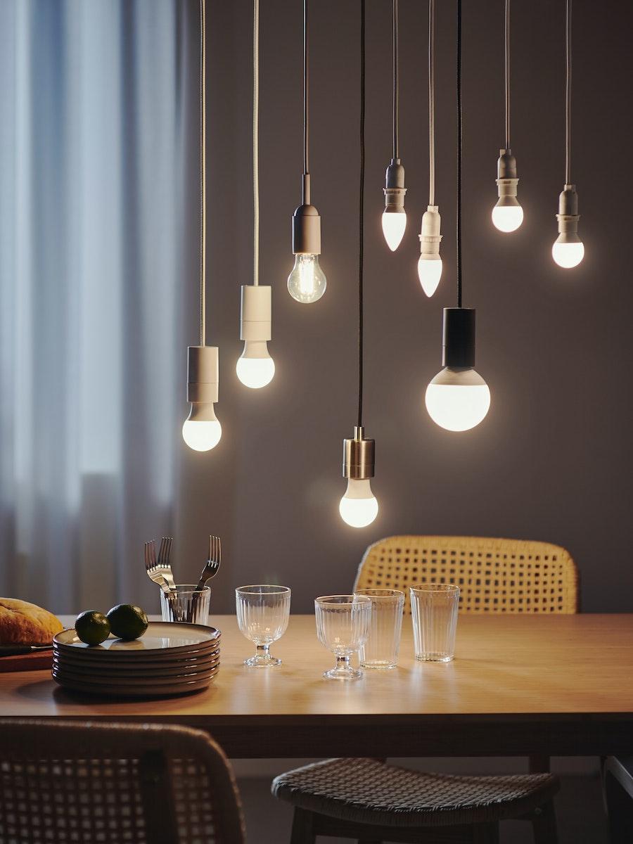 Table éclairée par la lumière douce d’ampoules LED IKEA suspendues au plafond. 