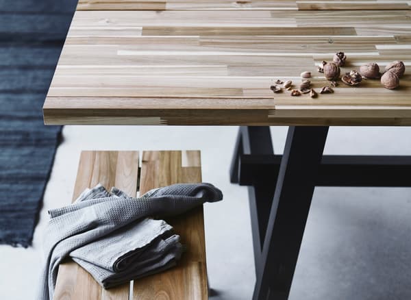 Table rectangulaire de style scandinave et banc SKOGSTA fabriqués en bois avec des variations de grain et de couleur.