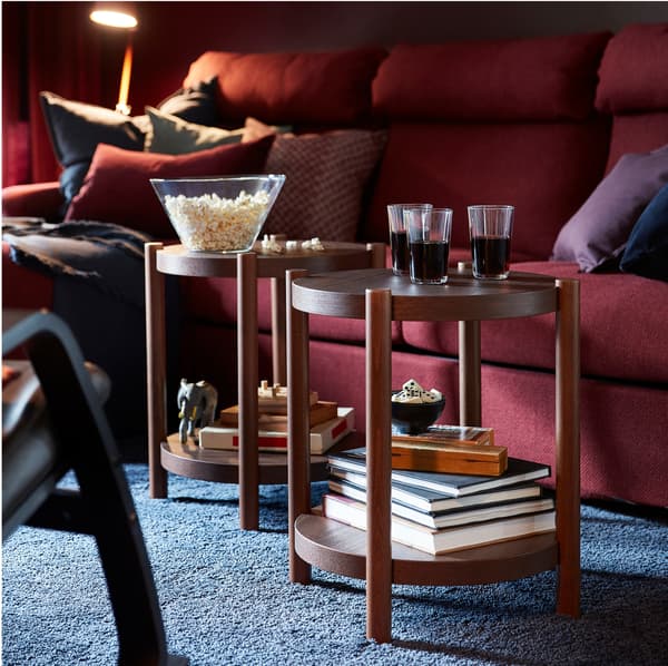 Tables d’appoint LISTERBY rondes en bois brun sur lesquelles sont posées collation et boissons. 