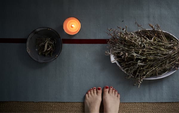 Tapis de yoga, bougie et bols d’herbes.