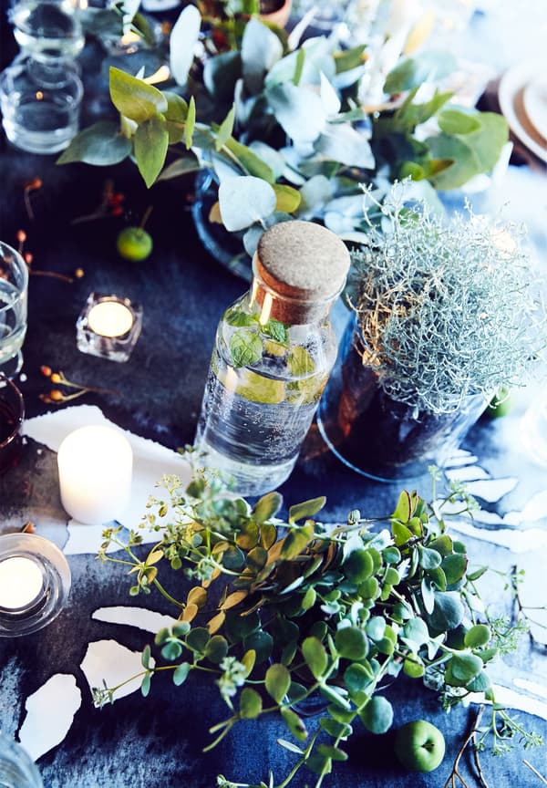 Tavola decorata con bacche, portacandele, candele bianche e rametti.