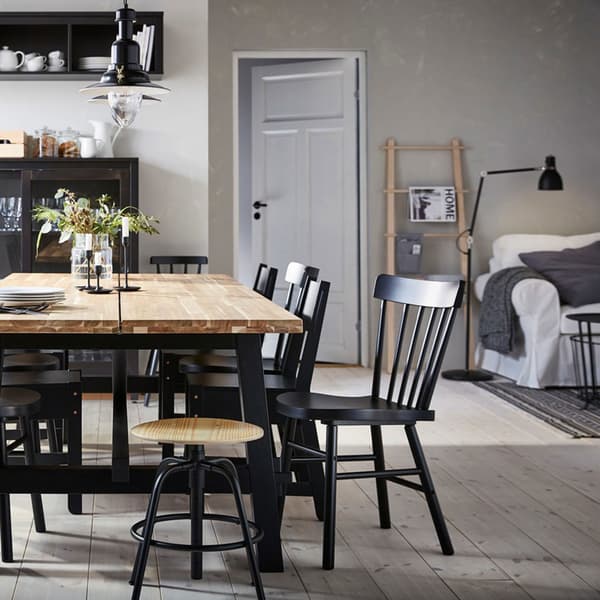Tavolo SKOGSTA in acacia al centro di una zona pranzo beige e nera, circondato da sedie nere di diverso tipo – IKEA