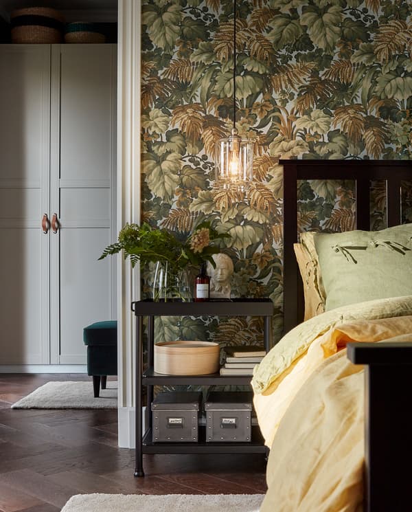 طاولة جانبية KORNSJÖ بجوار سرير مستخدمة كطاولة جانبية للسرير. مع أغراض تزيينية، وكتب وصناديق مخزنة.