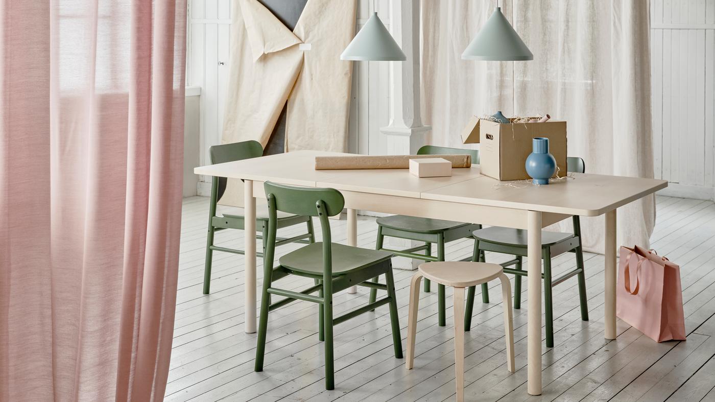 طاولة قابلة للتمديد RÖNNINGE في وضع التمديد في غرفة طعام يجري فيها نشاط تغليف مستمر.