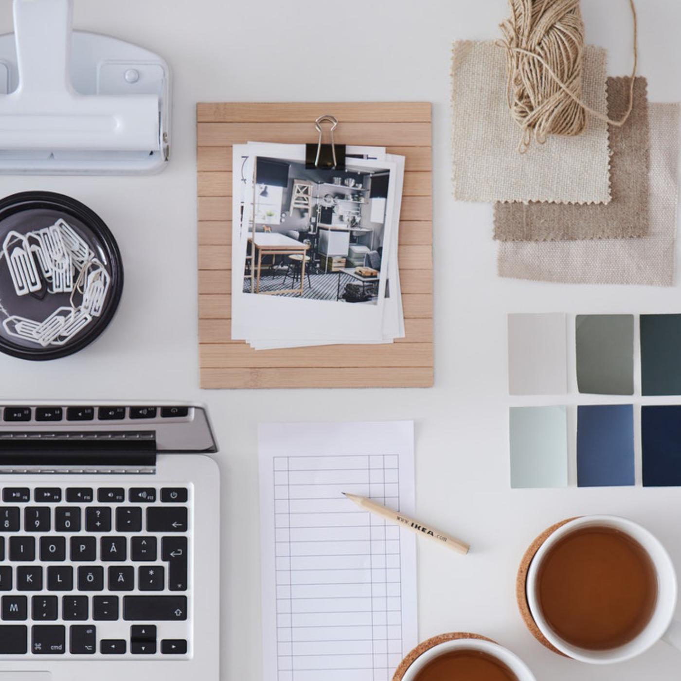 テーブルの上に、紅茶2杯、パソコン、ノート、いろいろな色の四角い厚紙が置かれている