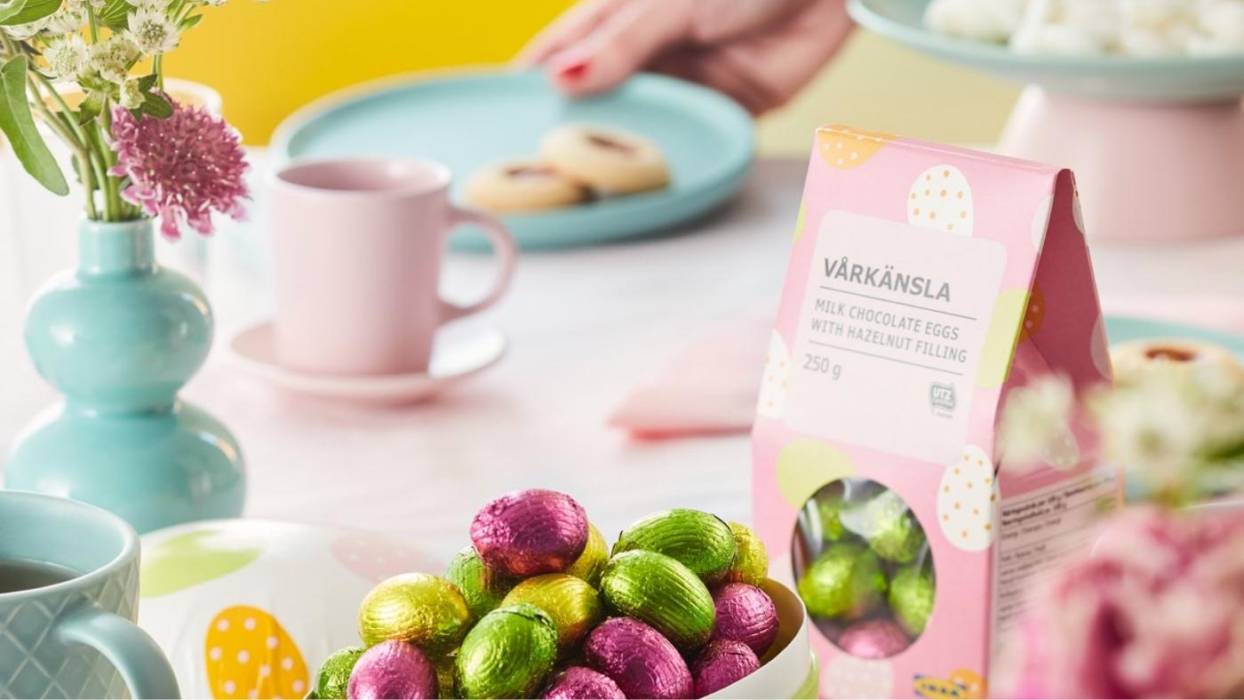 テーブルの上にピンクとブルーのパステルカラーの食器とデコレーション、手前にイースターエッグの形のチョコレート。