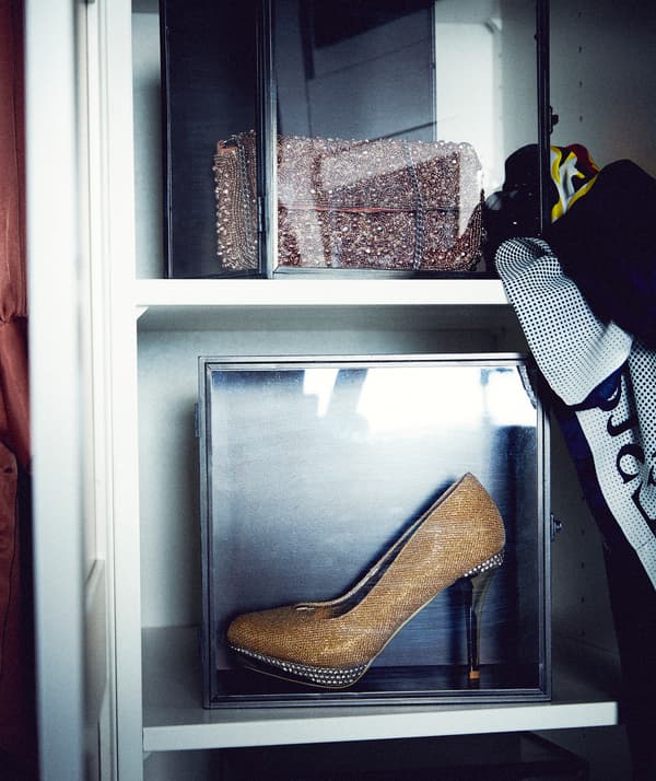 Teil eines Kleiderschranks mit einem SAMMANHANG Sammlerrahmen, in dem ein hochhackiger Schuh präsentiert wird.