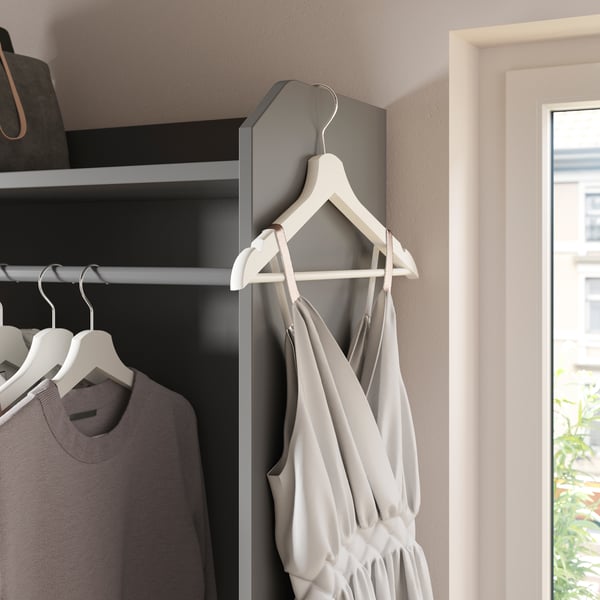 Teil eines offenen HAUGA Kleiderschranks mit drei Schubladen in Grau, in dem Hemden auf Bügeln hängen, ein Kleid hängt außen am Schrank.