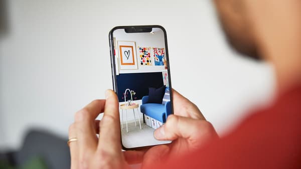 Telefon, który trzyma osoba, wyświetla inspirację pokoju dziennego z niebieską kanapą.