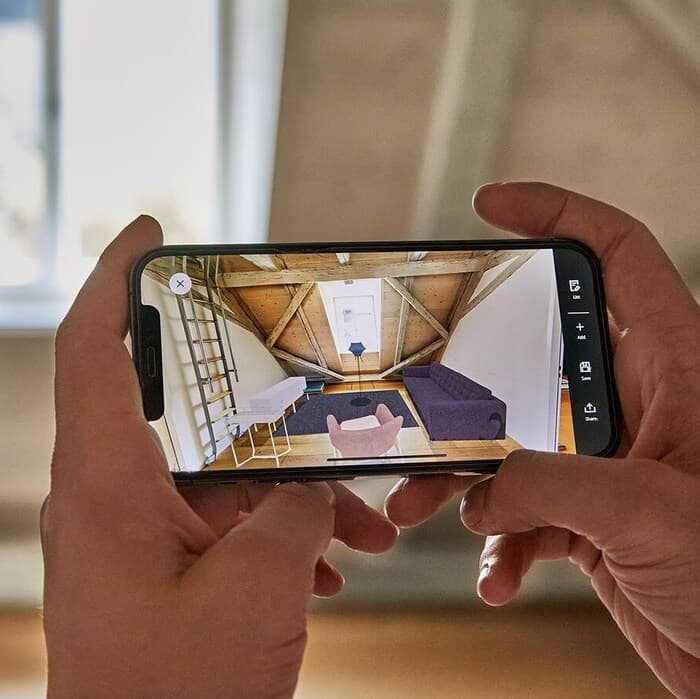 Telefon w dłoni, na którym widnieje pokój w aplikacji KREATIV