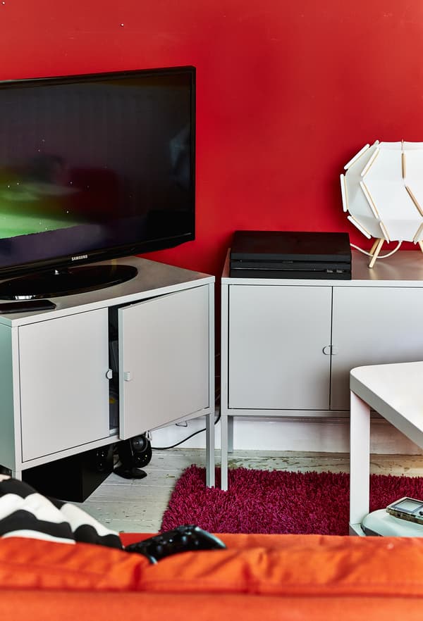Téléviseur et console de jeux déposés sur des meubles de rangement en métal.
