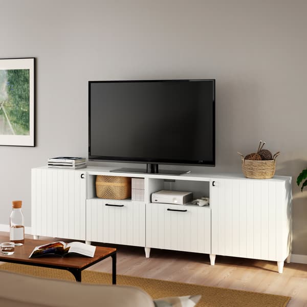 Téléviseur noir sur un banc TV BESTÅ blanc avec des pieds KABBARP blancs et des portes/faces de tiroir SUTTERVIKEN blanches.