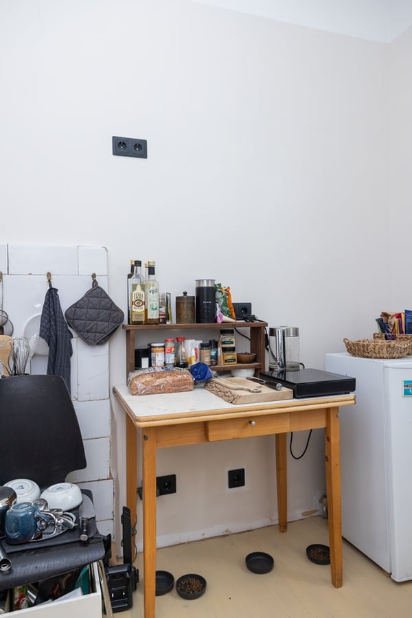 Temporary kitchen area with a small table, appliances and dishes in a compact room.