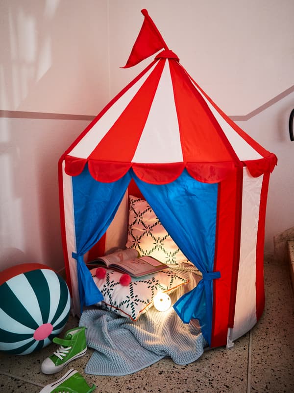 Tenda per bambini CIRKUSTÄLT ai piedi delle scale, con morbidi tessili e un libro aperto all'interno, accanto un giocattolo morbido KÄPPHÄST - IKEA