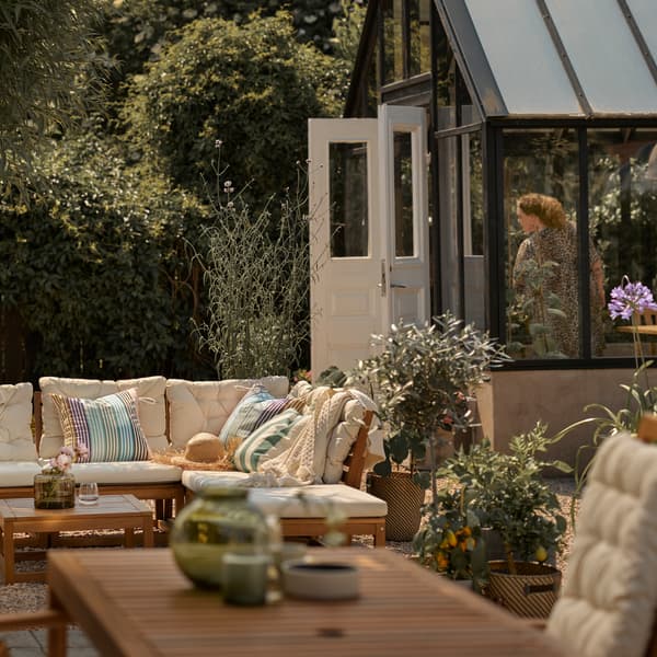 Terras met lichtbruine modulaire zitbank voor buiten met beige kussens, plus lichtbruine buitentafel met tuinstoel.