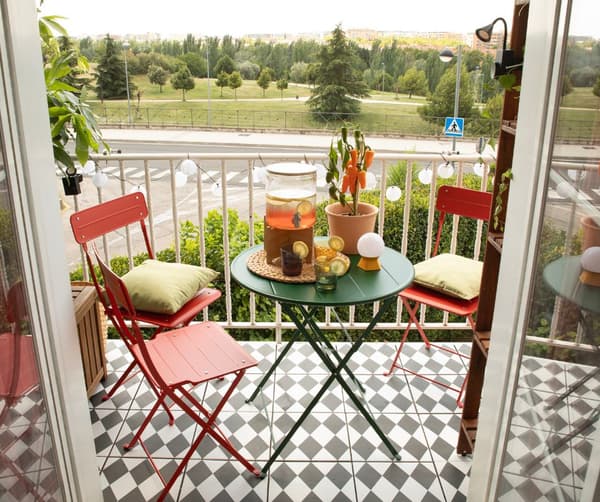 Terraza con sillas y mesa plegable, suelo hidráulico, guirnalda y cojines.
