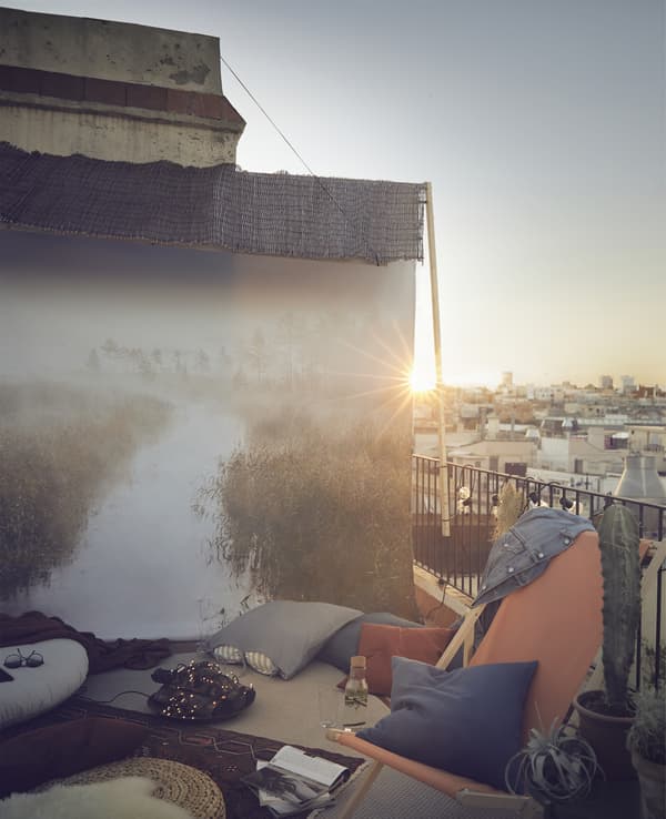 Terrazza con sedie, cuscini, tappeti e immagine di un grande paesaggio sulla parete.