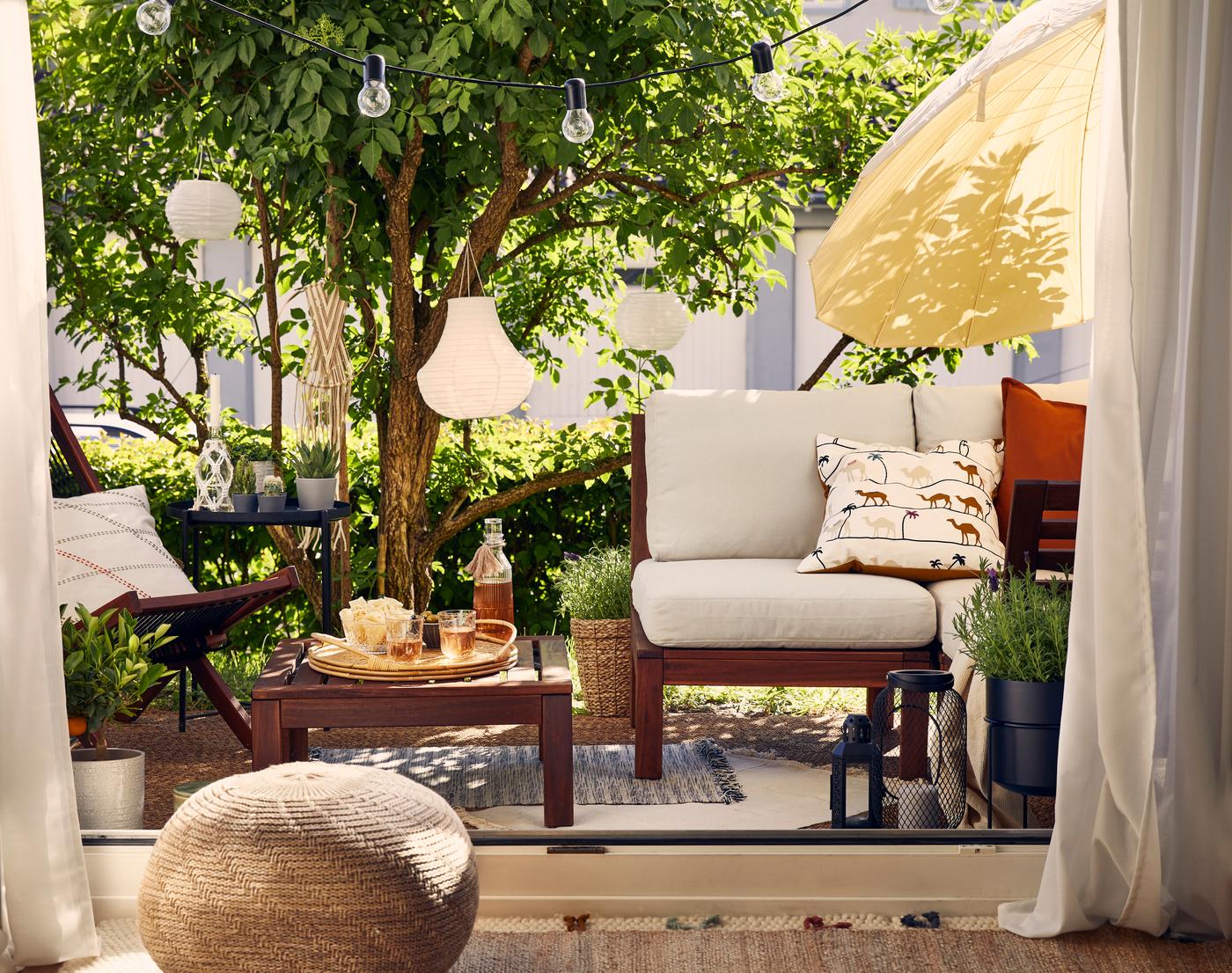 Terrazza giardino con salotto in legno, lanterne e luci di fata