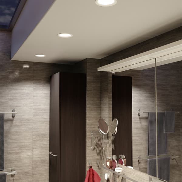 Teto da casa de banho com três projetores LED embutidos que são reguláveis, e um comando TRÅDFRI montado na parede mais abaixo.