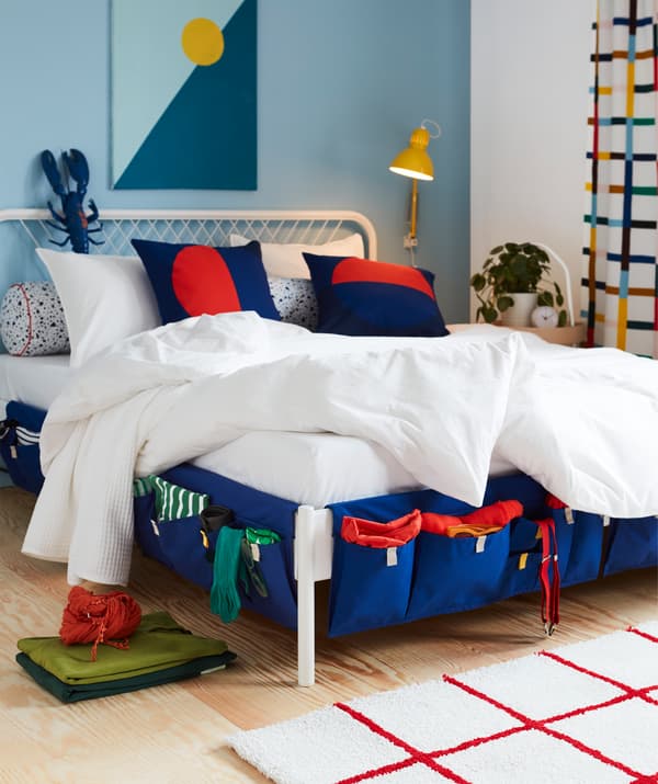 Textile storage with blue MÖJLIGHET bed pocket, used to store socks, braces and other accessories, hanging from the sides of the bed.
