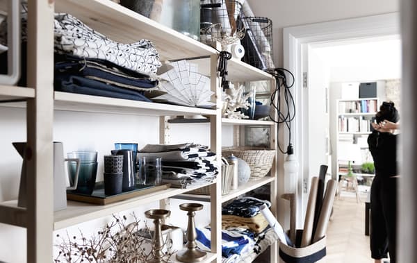 Textiles et service de table exposés dans un rangement ouvert.