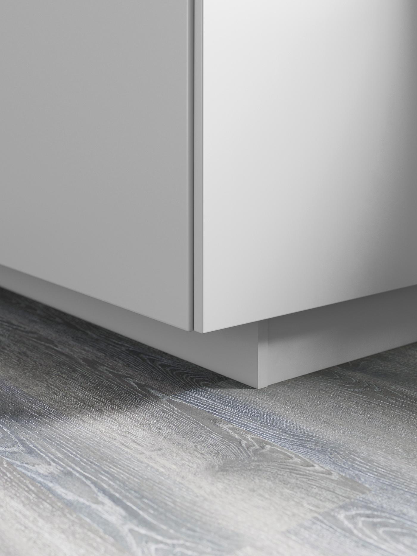 The bottom corner of a gray base cabinet with a matching plinth underneath.