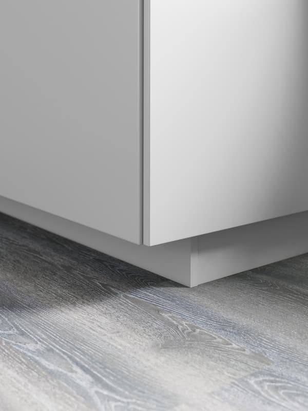 The bottom corner of a grey base cabinet with a matching plinth underneath.
