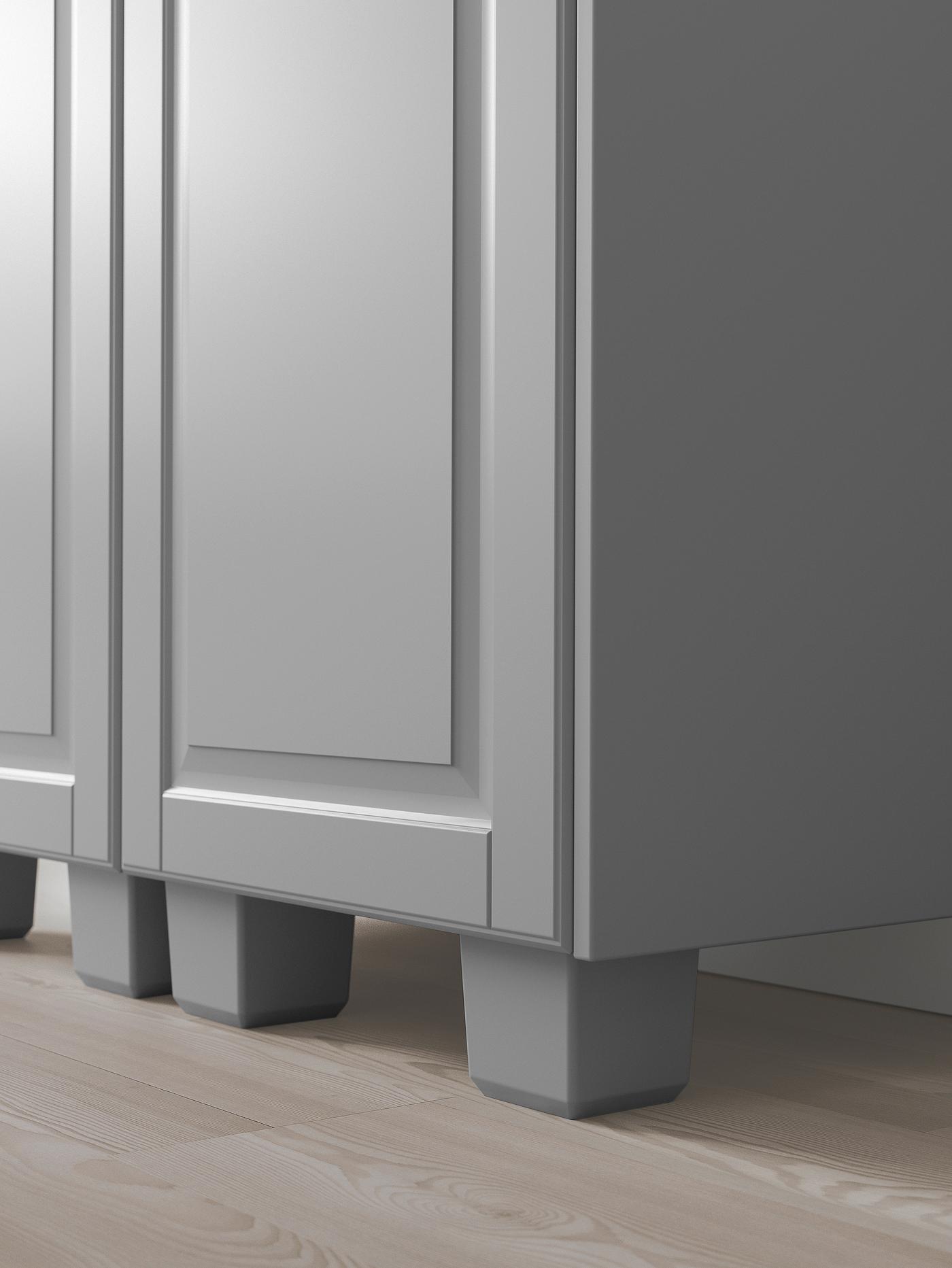 The bottom corner of a grey kitchen cabinet with matching grey legs.