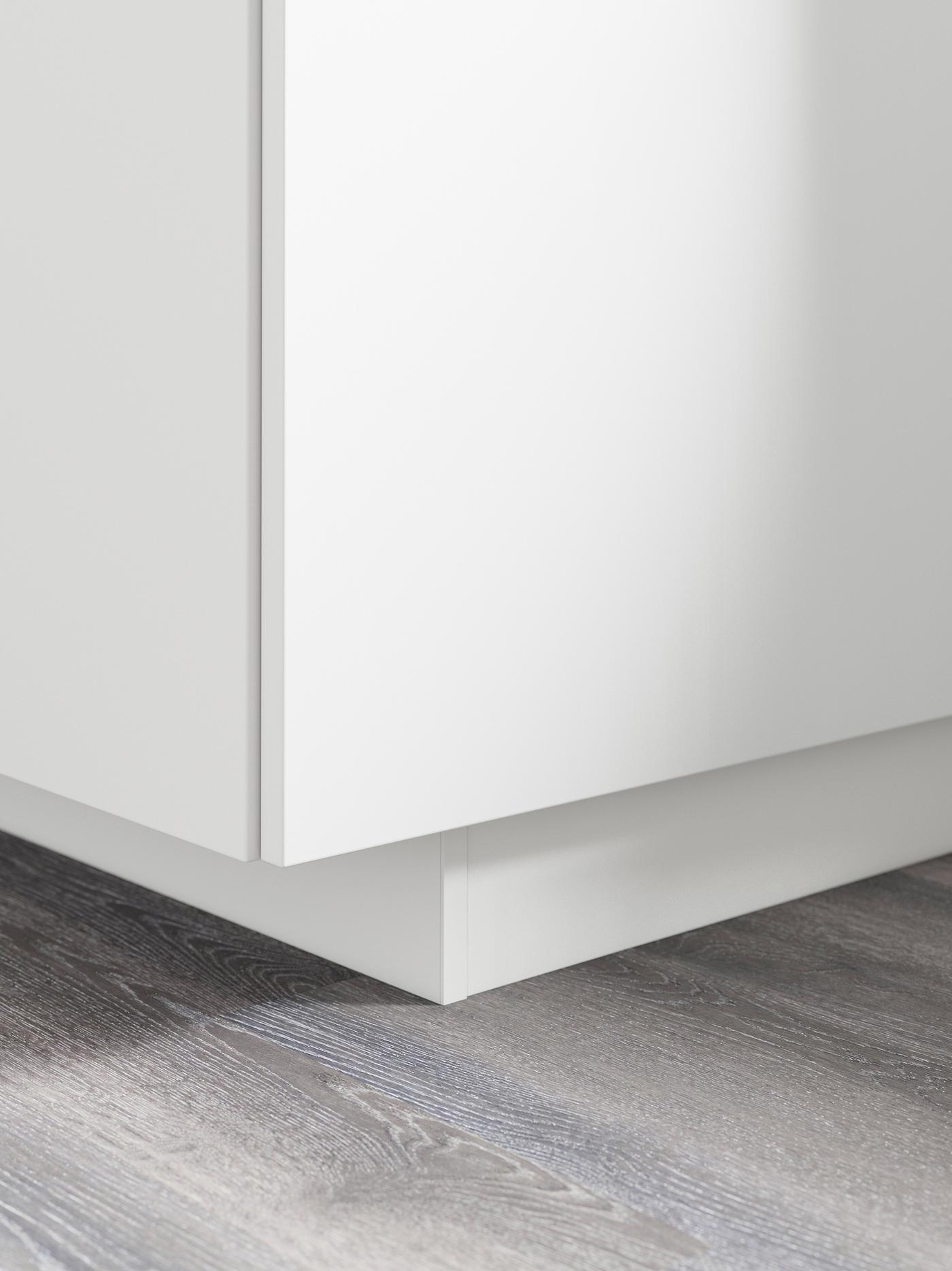 The bottom corner of a white base cabinet with a matching plinth underneath.