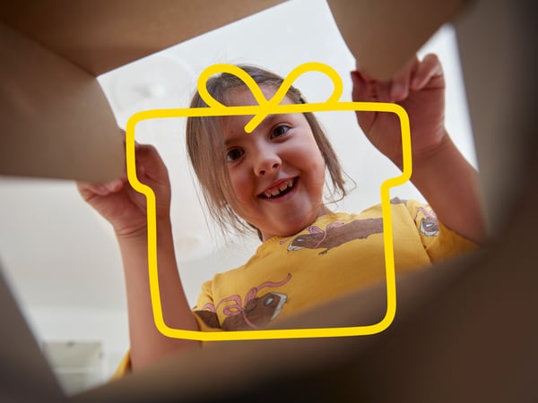 The child peeks into the cardboard box and smiles.